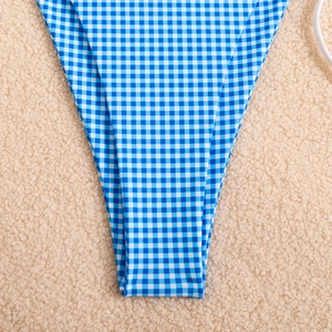 Detail of blue and white gingham bikini bottom on a soft beige textured background
