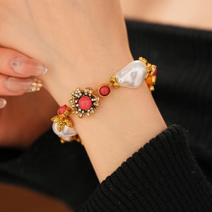 Detail of vintage gold bracelet with white pearls, red beads and rhinestone flowers