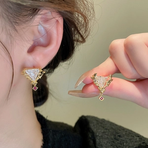 Boucles d'oreilles triangles dorées vintage avec zircones rouges et clairs sur l'oreille