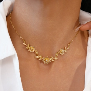 Détail du collier floral doré avec bourgeons en cristal porté sur une chemise blanche
