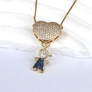 Gold box chain necklace with a zircon heart and cute boy pendant on white stone