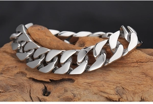 Gros plan d'un bracelet gourmette argenté épais poli sur une branche en bois