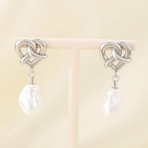 Detail of silver heart-shaped knot earrings with hanging white baroque pearls on display
