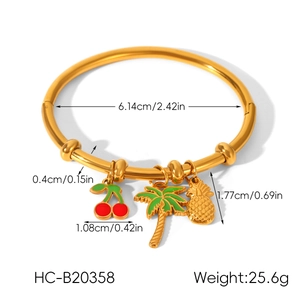 Dettaglio del bracciale dorato con ciondoli smaltati ciliegia, palma e ananas