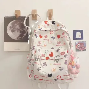 Detailed view of white cartoon backpack with colorful heart prints and Happy text
