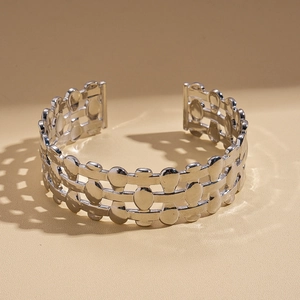Macro shot of silver wide-open cuff bracelet with hollow geometric patterns and shadows