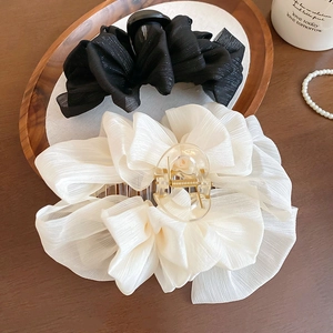 Detail showing large pleated chiffon hair claws in black and beige with a pearl setting