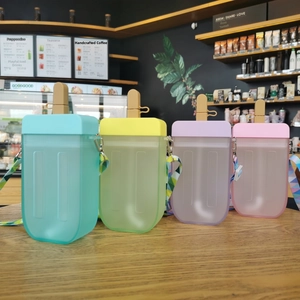 Close-up of colorful popsicle-shaped water bottles with straps on a wooden table