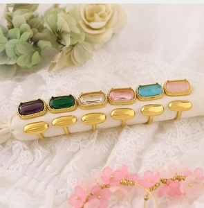 Vue détaillée de six bagues dorées avec cristaux colorés sur un tissu en dentelle