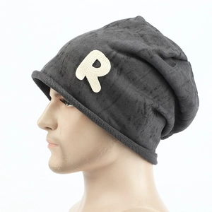 Détail du bonnet en tricot gris foncé avec écusson lettre R et bord roulé élégant