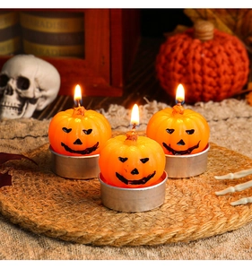 Three lit orange pumpkin candles on a woven mat with Halloween themed skull decor