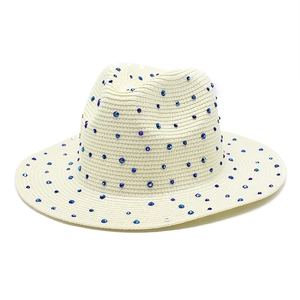 Detailed macro view of cream straw fedora hat with elegant blue gradient rhinestones