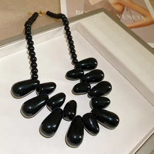 Gros plan détaillé du collier en acrylique noir avec pendentifs en forme de goutte