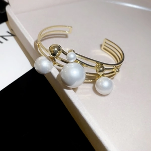 Macro detail of multi-layer gold bangle with elegant white pearls and hollow frame