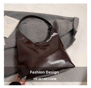 Detail of dark brown glossy patent leather hobo bag with smooth shoulder strap texture