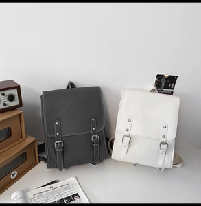 Detail of vintage soft leather backpacks in dark grey and white with silver buckles