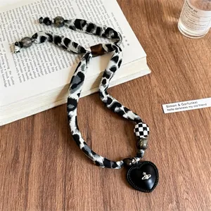 Dettaglio della collana in corda leopardata con pendente a cuore in pelle e logo Saturno