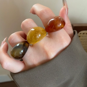 Close-up of stacked colorful resin rings in brown, amber and yellow on woman's hand