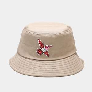 Detailed view of hummingbird embroidery on beige cotton bucket hat with stitched brim