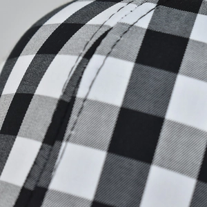 Close-up of buffalo check baseball cap with double stitching detail on fabric joints