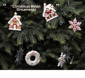 Close-up of resin gingerbread house and snowflake ornaments on a green Christmas tree