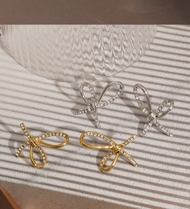 Macro detail of bow-shaped stud earrings featuring delicate zircons in gold and silver