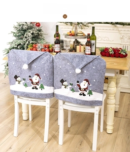 Detail of gray Christmas chair covers with snowman print and plush balls in home setting