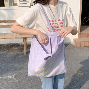 Detail view of purple canvas tote bag showing large capacity and embroidered letters