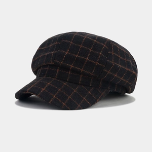 Detail of a dark black plaid newsboy cap showing wool-like fabric texture and check pattern