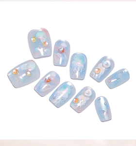 Dettaglio di unghie finte blu oceano sfumate con glitter cat-eye e perle a bolla