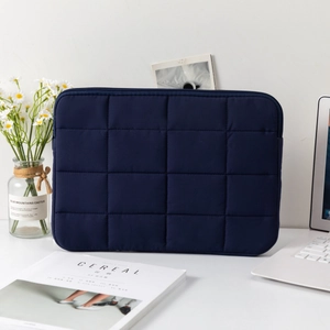 Detailed view of dark blue quilted laptop sleeve on a minimalist desk with daisy decor