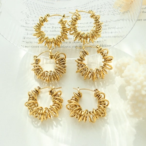 Three pairs of golden spiral geometric hoop earrings in a minimalist jewelry display