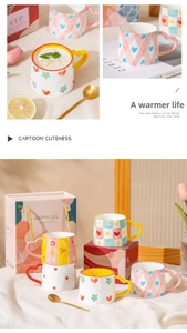 Detail of ceramic mugs with heart handles and golden spoons in gift box packaging