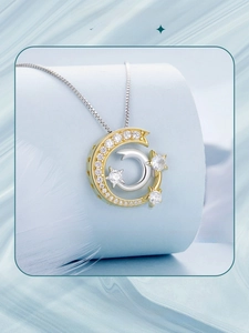 Detail of s925 silver star and moon pendant necklace with cubic zirconia on a blue display