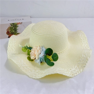 Detailed close-up of beige straw sun hat with decorative 3D floral accents and woven texture