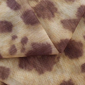 Detailed close-up of brown leopard print mesh fabric with soft folds and sheer texture