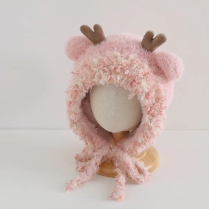 Detail of soft pink faux mink fur winter hat with deer antlers and pom-pom earflaps