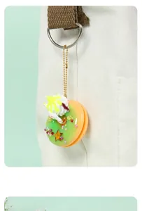 Gros plan d'un porte-clés donut vert et orange avec crème sur un sac en toile blanc