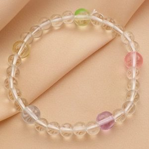 Détail d'un bracelet en perles colorées avec pierres pastels sur un tissu en satin doux