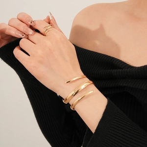 Dettaglio del bracciale geometrico a fascia dorata e anello abbinato su modella