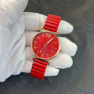 Detail of red embossed leaf texture dial and golden case on elastic strap watch