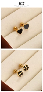 Détail de boucles d'oreilles trèfle et cœur dorées avec émail noir et fermoir à vis