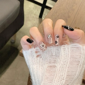 Close-up of press-on nails with 3D floral accents and glitter on a natural manicure