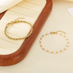 Detail of 18k gold plated twisted rope and pearl beads bracelet on a jewelry tray