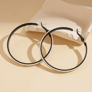 Vue détaillée de grandes boucles d'oreilles rondes contrastées noir et blanc avec texte