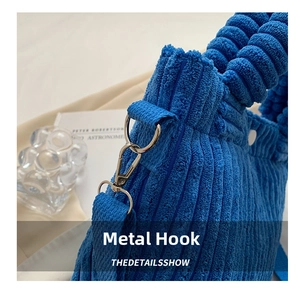 Detailed close-up of the silver hardware hook and corduroy fabric on this blue bucket bag