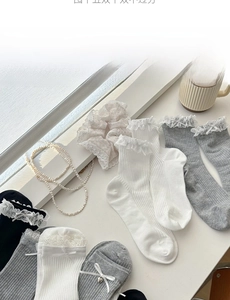 Close-up of cotton socks with lace edges and delicate ribbon bows in neutral colors