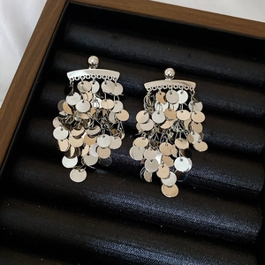 Close-up of silver sequin tassel earrings on black velvet tray for luxury jewelry display