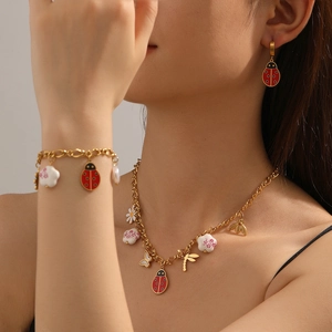 Model wearing gold insect jewelry set with ladybug and bee necklace, earrings and bracelet