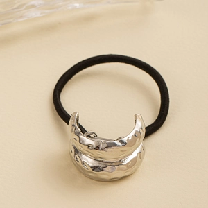 Macro shot of minimalist black elastic hair tie with silver hammered metal texture detail